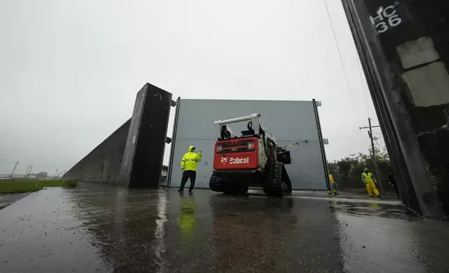 Workers from the Southeast Louisiana Flood Protection Authority-West close floodgates along the Harvey Canal, just outside the New Orleans city limits, in anticipation of Tropical Storm Francine, in Harvey, La., Tuesday, Sept. 10, 2024. (AP Photo/Gerald Herbert)