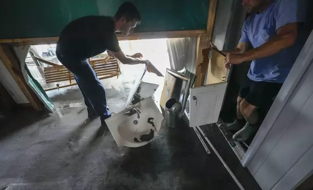 Jansen Pellegrin, right, and his brother-in-law Allen McCoy gut a bathroom as they help clean out their family's camp, which took on a storm surge, in the aftermath of Hurricane Francine, in Cocodrie, La., Thursday, Sept. 12, 2024. (AP Photo/Gerald Herbert)