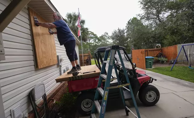 Dave McCurley boards up the windows to his home in advance of Tropical Storm Helene, expected to make landfall as a hurricane, in Ochlockonee Bay, Fla., Wednesday, Sept. 25, 2024. (AP Photo/Gerald Herbert)