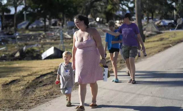 A group from St. Augustine, Fla. that arrived to help storm victims, who did not want to give their names, walk to the damaged First Baptist Church to pray in the aftermath of Hurricane Helene, in Horseshoe Beach, Fla., Sunday, Sept. 29, 2024. (AP Photo/Gerald Herbert)