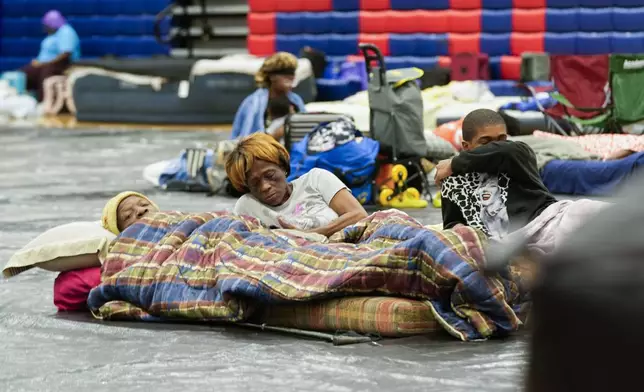 Bobby Joe Edwards, Sr., and his wife Lillie Edwards, of Walkalla, Fla., and their grandson Tavarrious Dixon, rest inside a hurricane evacuation shelter at Fairview Middle School, ahead of Hurricane Helene, expected to make landfall here today, in Leon County, Fla., Thursday, Sept. 26, 2024. (AP Photo/Gerald Herbert)