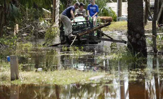 People move debris from a damaged home in the aftermath of Hurricane Helene, in Horseshoe Beach, Fla., Saturday, Sept. 28, 2024. (AP Photo/Stephen Smith)