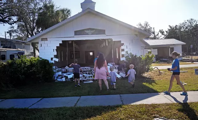 A group from St. Augustine, Fla. that arrived to help storm victims, who did not want to give their names, pray outside the damaged First Baptist Church in the aftermath of Hurricane Helene, in Horseshoe Beach, Fla., Sunday, Sept. 29, 2024. (AP Photo/Gerald Herbert)