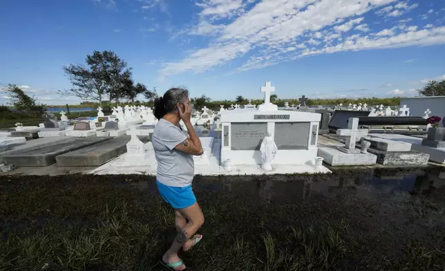 Lori-Ann Bergeron checks on the graves of her sister and mother to see that they were not disturbed by flooding, in the aftermath of Hurricane Francine, in Dulac, La., Thursday, Sept. 12, 2024. (AP Photo/Gerald Herbert)