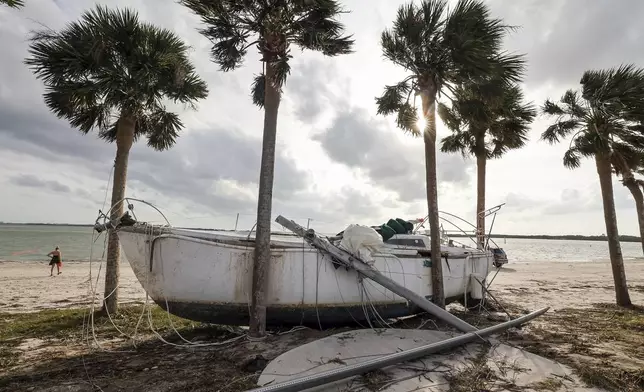 A boat pushed ashore on to the Dunedin Causeway by floodwaters from Hurricane Helene, Friday, Sept. 27, 2024, in Dunedin, Fla. (AP Photo/Mike Carlson)