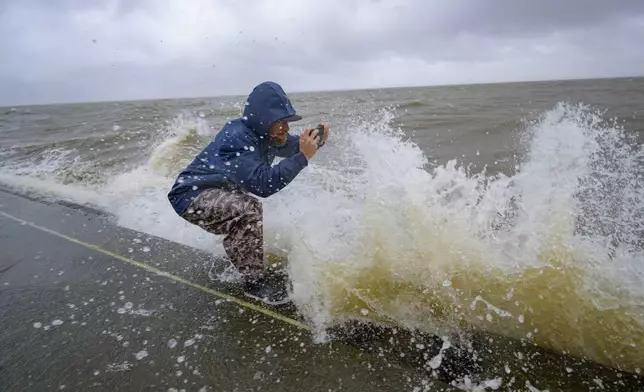 Conrad Bach gets doused with lake water while looking at waves from the wind and rain from Hurricane Francine along Lakeshore Drive along Lake Ponchartrain in New Orleans, Wednesday, Sept. 11, 2024. (AP Photo/Matthew Hinton)