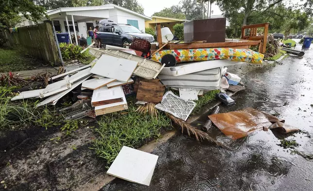 Residents clean contents of their home after flooding from Hurricane Helene on Davis Island Saturday, Sept. 28, 2024, in Tampa, Fla. (AP Photo/Mike Carlson)