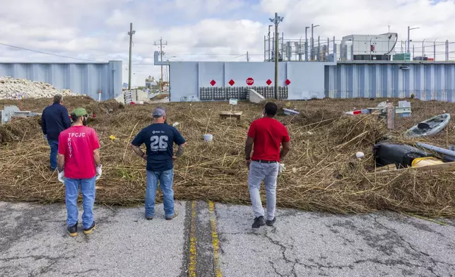 Cleaning crews view the pile of detritus and marsh grass that piled up against a flood wall from Hurricane Francine in Terrebonne Parish, La., Thursday, Sept. 12, 2024. (Chris Granger/The Times-Picayune/The New Orleans Advocate via AP)