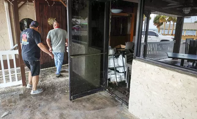 Staff of the Inn On The Gulf clean up after their restaurant flooded with surge from Hurricane Helene Friday, Sept. 27, 2024, in Hudson, Fla. (AP Photo/Mike Carlson)