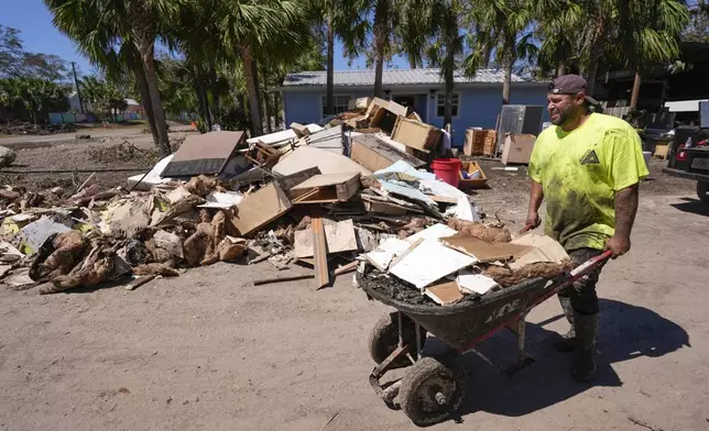 Jose Salazar dumps debris as he helps gut a property that took on a storm surge in the aftermath of Hurricane Helene, in Steinhatchee, Fla., Sunday, Sept. 29, 2024. (AP Photo/Gerald Herbert)