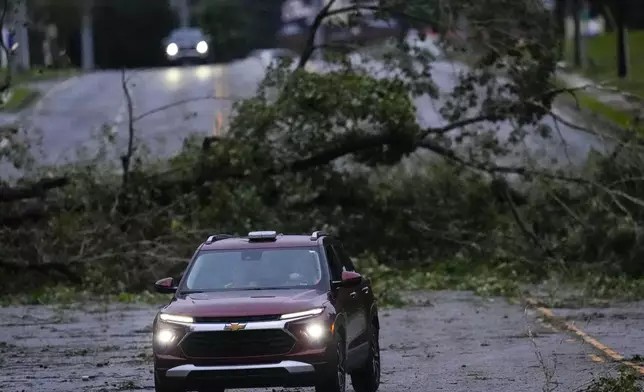 Vehicles move slowly around trees that have fallen after Hurricane Helene, Friday, Sept. 27, 2024, in Valdosta, Ga. (AP Photo/Mike Stewart)