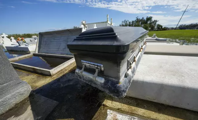 A casket sits on an adjacent tomb after floating out of its tomb at Holy Family Cemetery No. 2, Thursday, Sept. 12, 2024, Dulac, La., following floodinig from Hurricane Francine. (AP Photo/Gerald Herbert)