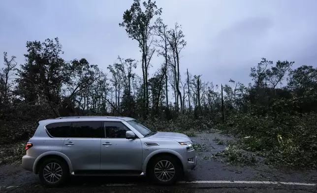 Vehicles move slowly around trees that have fallen after Hurricane Helene moved through the area, Friday, Sept. 27, 2024, in Valdosta, Ga. (AP Photo/Mike Stewart)