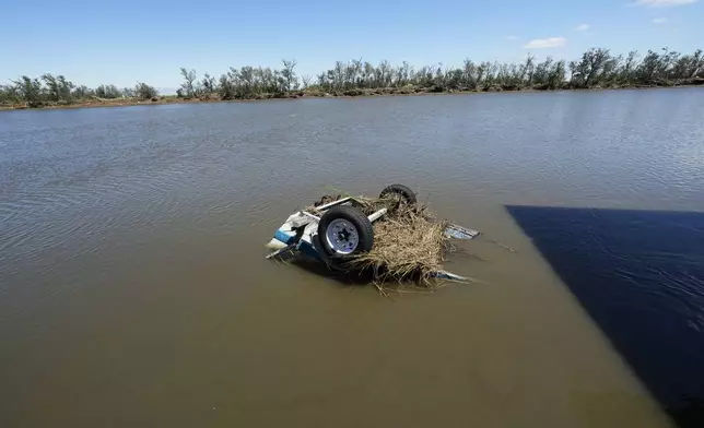 An overturned boat sits in the bayou behind the home of resident Bill Andrews in the aftermath of Hurricane Francine in Cocodrie, La., Thursday, Sept. 12, 2024. (AP Photo/Gerald Herbert)