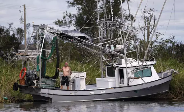 Chad Luke calls out to family for help in getting his shrimp boat from being grounded on the bank in the aftermath of Hurricane Francine, Thursday, Sept. 12, 2024, in Dulac, La. (AP Photo/Gerald Herbert)