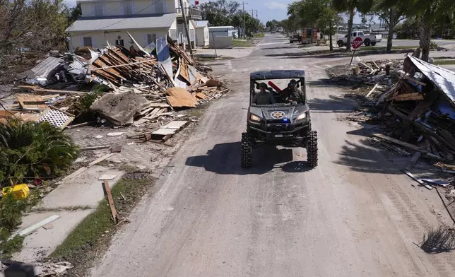 Law enforcement officers from the Florida Fish Wildlife and Conservation Commission drive past destruction in the aftermath of Hurricane Helene, in Cedar Key, Fla., Friday, Sept. 27, 2024. (AP Photo/Gerald Herbert)