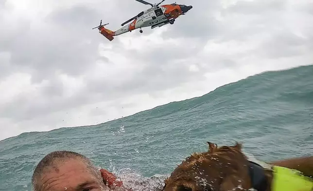 This photo provided by U.S. Coast Guard District Seven (USCGSoutheast) shows a man and his dog being rescued after his sailboat became disabled during Hurricane Helene approximately 25 miles off Sanibel Island, Fla., on Thursday, Sept. 26, 2024. (U.S. Coast Guard District Seven via AP)