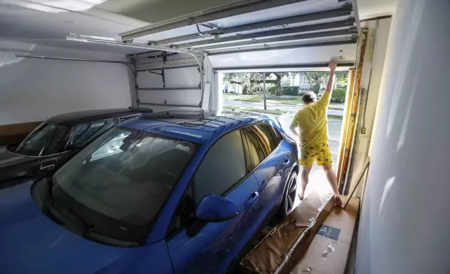 Max Ceratti, 19, lifts up the garage door to examine the damage done to his car from Hurricane Helene at his home around the Sunset Park neighborhood on Friday, Sept. 27, 2024, in Tampa, Fla. (Jefferee Woo/Tampa Bay Times via AP)