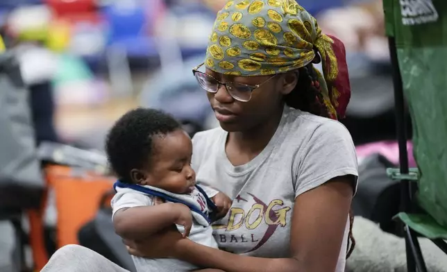 Katoria Harvey, of Tallahassee, sits with her niece Ny'Year Harvey, 3 months, inside a hurricane evacuation shelter at Fairview Middle School, ahead of Hurricane Helene, expected to make landfall here today, in Leon County, Fla., Thursday, Sept. 26, 2024. (AP Photo/Gerald Herbert)