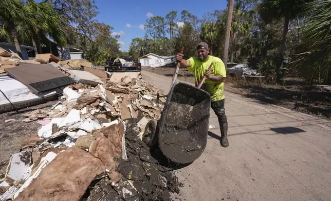 Jose Salazar dumps debris as he helps gut a property that took on a storm surge in the aftermath of Hurricane Helene, in Steinhatchee, Fla., Sunday, Sept. 29, 2024. (AP Photo/Gerald Herbert)