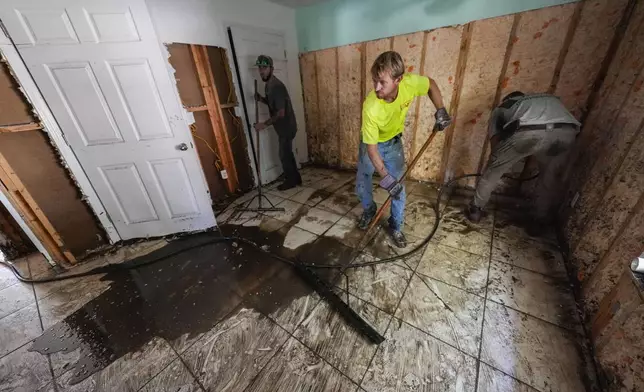 Workers clean and gut a property that was flooded from the storm surge, in the aftermath of Hurricane Helene, in Steinhatchee, Fla., Sunday, Sept. 29, 2024. (AP Photo/Gerald Herbert)