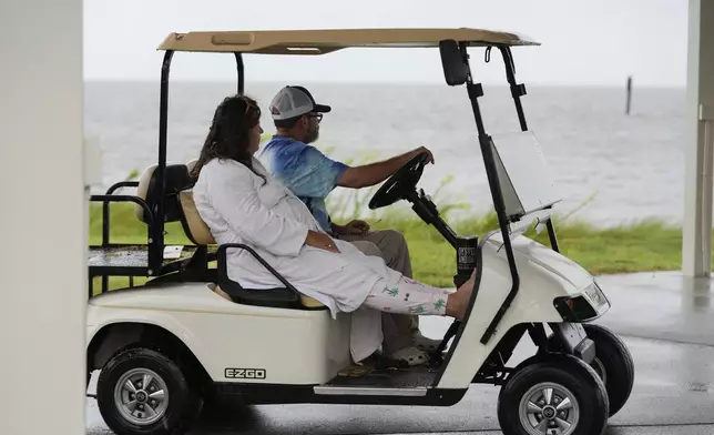 Bob and Lisa Danzey, residents, look out at the water from their golf cart ahead of Hurricane Helene, expected to make landfall here today, in Shell Point Beach, Fla., Thursday, Sept. 26, 2024. (AP Photo/Gerald Herbert)