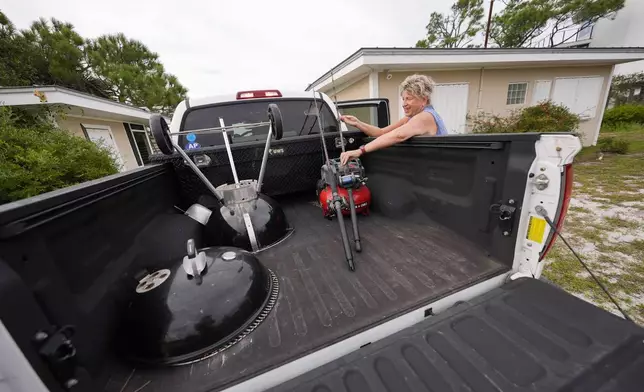 Paulette McLin loads items into their truck as they prepare their summer home ahead of Hurricane Helene, expected to make landfall Thursday evening, in Alligator Point, Fla., Wednesday, Sept. 25, 2024. (AP Photo/Gerald Herbert)