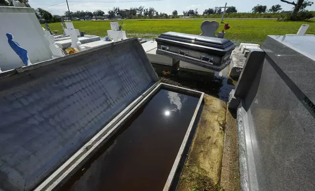 A casket sits on an adjacent tomb after floating out of its tomb at Holy Family Cemetery No. 2, Thursday, Sept. 12, 2024, Dulac, La., following floodinig from Hurricane Francine. (AP Photo/Gerald Herbert)