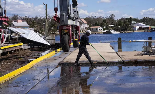 Workers clean up a dock where a boat shed was destroyed in the aftermath of Hurricane Helene, in Jena, Fla., Sunday, Sept. 29, 2024. (AP Photo/Gerald Herbert)