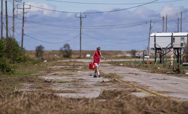 Resident Bill Andrews walks to a store 1.5 miles away to see if he can get gas, after Hurricane Francine flooded his truck, in Cocodrie, La., Thursday, Sept. 12, 2024. (AP Photo/Gerald Herbert)