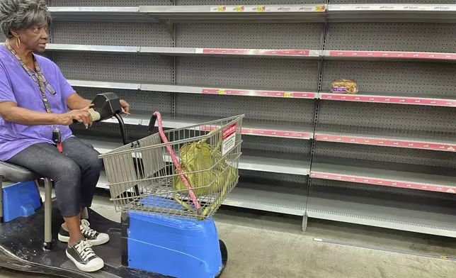 A shopper passes by empty shelves in the bread section of a Walmart, Wednesday, Sept. 25, 2024 in Tallahassee, Fla. Grocery stores and gas stations were seeing heavy traffic in advance of Hurricane Helene, expected to make landfall Thursday night in the Big Bend area. (AP Photo/Phil Sears)