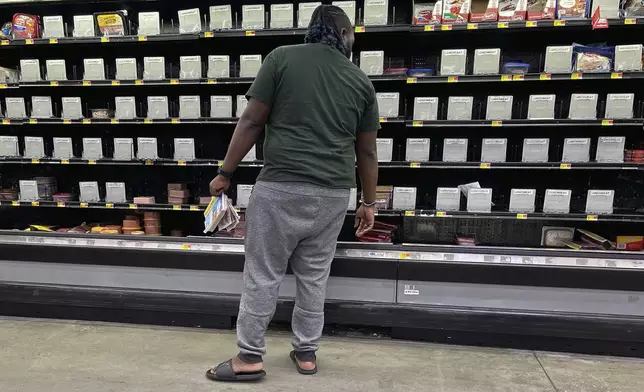 A shopper checks out nearly empty shelves in the lunch meat section of a Walmart, Wednesday, Sept. 25, 2024 in Tallahassee, Fla. Grocery stores and gas stations were seeing heavy traffic in advance of Hurricane Helene, expected to make landfall Thursday night in the Big Bend area. (AP Photo/Phil Sears)