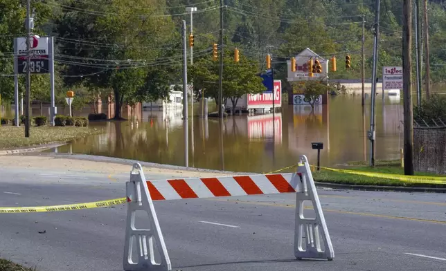 A barrier blocks a flooded Carbon City Road due to the torrential rain from Hurricane Helene , Saturday, Sept. 28, 2024 in downtown Morganton, N.C. (AP Photo/Kathy Kmonicek)