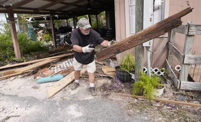 Dennis Johnson cleans out debris from his mother-in-law's heavily damaged home in the aftermath of Hurricane Helene, in Horseshoe Beach, Fla., Saturday, Sept. 28, 2024. (AP Photo/Gerald Herbert)