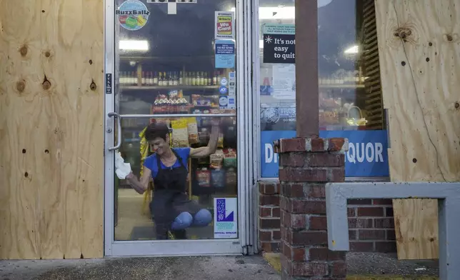 Tammy Corey, a clerk at a mostly boarded up Birdies Food and Fuel, keeps the main door windows free of condensation, Wednesday, Sept. 11, 2024, in Luling, La., ahead of Hurricane Francine. (David Grunfeld/The Times-Picayune/The New Orleans Advocate via AP)