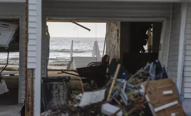 The sun shines through a hole in a building after storm surge from Hurricane Helene sent tons of sand into homes, Saturday, Sept. 28, 2024, in Madeira Beach, Fla. (Luis Santana/Tampa Bay Times via AP)