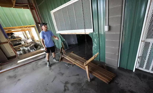 Jansen Pellegrin examines a damaged porch swing as he helps clean out his family's camp, that took on a storm surge, in the aftermath of Hurricane Francine, in Cocodrie, La., Thursday, Sept. 12, 2024. (AP Photo/Gerald Herbert)