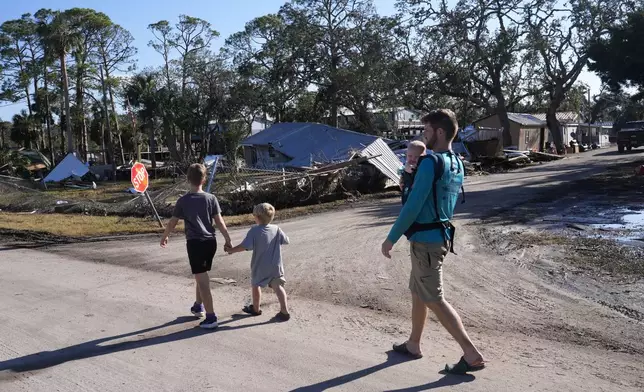 A group from St. Augustine, Fla. that arrived to help storm victims, who did not want to give their names, walk to the damaged First Baptist Church to pray in the aftermath of Hurricane Helene, in Horseshoe Beach, Fla., Sunday, Sept. 29, 2024. (AP Photo/Gerald Herbert)