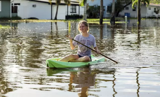 Halle Brooks kayaks down a street flooded by Hurricane Helene in the Shore Acres neighborhood Friday, Sept. 27, 2024, in St. Petersburg, Fla. (AP Photo/Mike Carlson)