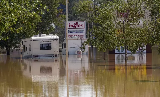 A couple of RVs are abandoned in the flooded Ingles parking lot due to the torrential rains from Hurricane Helene, Saturday, Sept. 28, 2024, in Morganton, N.C. (AP Photo/Kathy Kmonicek)