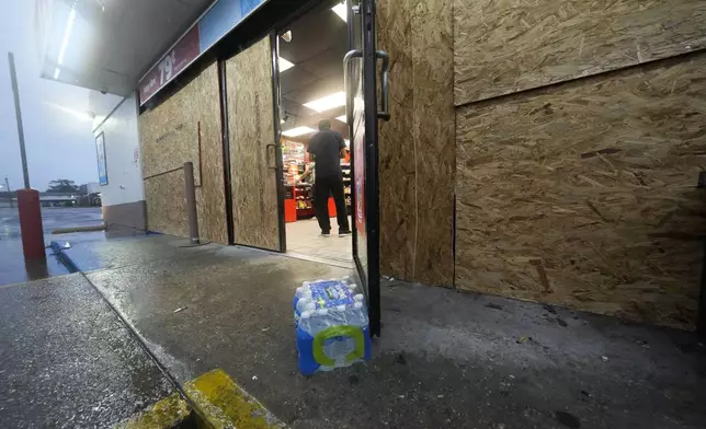 A customer enters one of the few gas stations open, boarded up in anticipation of Hurricane Francine, in Morgan City, La., Wednesday, Sept. 11, 2024. (AP Photo/Gerald Herbert)