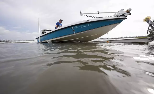 Bo Manausa pulls his boot out of the water ahead of Hurricane Helene, expected to make landfall Thursday evening, in Alligator Point, Fla., Wednesday, Sept. 25, 2024. (AP Photo/Gerald Herbert)