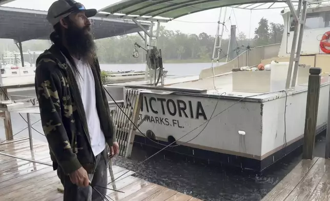 Darren Archer works on tying down a cover over a boat named the Susan D. docked in St. Marks, Fla. on Thursday Sept. 26, 2024. Archer, who works for the St. Marks Seafood company, plans to ride out Hurricane Helene on a boat. (AP Photo/Kate Payne)