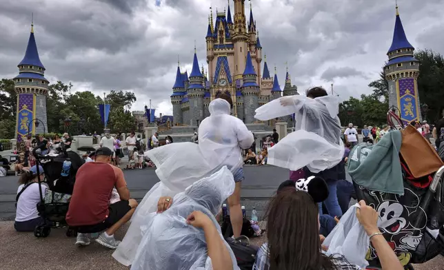 Guests at the Magic Kingdom break out ponchos at Cinderella Castle as bands of weather from Hurricane Helene move through Walt Disney World in Bay Lake, Fla., Thursday, Sept. 26, 2024. All four of Disney's Florida theme parks remained open Thursday as the storm passed to the west in the Gulf of Mexico. (Joe Burbank/Orlando Sentinel via AP)