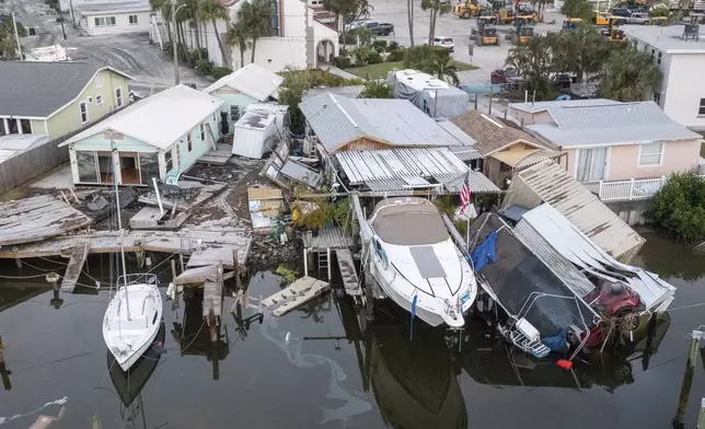 This aerial drone view shows damaged homes and a vehicle collapsed into water after storm surge from Hurricane Helene, Saturday, Sept. 28, 2024, in Madeira Beach, Fla. (Luis Santana/Tampa Bay Times via AP)