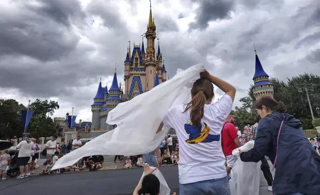 Guests at the Magic Kingdom break out ponchos at Cinderella Castle as bands of weather from Hurricane Helene move through Walt Disney World in Bay Lake, Fla., Thursday, Sept. 26, 2024. All four of Disney's Florida theme parks remained open Thursday as the storm passed to the west in the Gulf of Mexico. (Joe Burbank/Orlando Sentinel via AP)