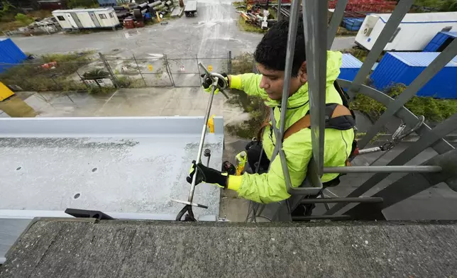 Delwyn Bodden, a worker for the Southeast Louisiana Flood Protection Authority-West climbs a ladder up a floodgate to lock it closed along the Harvey Canal, just outside the New Orleans city limits, in anticipation of Tropical Storm Francine, in Harvey, La., Tuesday, Sept. 10, 2024. (AP Photo/Gerald Herbert)