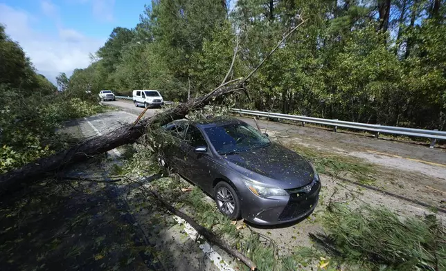 A tree rests on an adandoned car on Interstate 20 in the aftermath of Hurrican Helene Friday, Sept. 27, 2024, Grovetown, Ga. (AP Photo/John Bazemore)