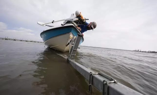 Bo Manausa pulls his boot out of the water ahead of Hurricane Helene, expected to make landfall Thursday evening, in Alligator Point, Fla., Wednesday, Sept. 25, 2024. (AP Photo/Gerald Herbert)