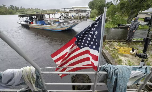 Joe Dempster, aboard the "Never Satisfied, left, and Jason Lireette, right, prepare to move a boat to a safer dock, Wednesday, Sept. 11, 2024, in Bayou Gauche, La., ahead of Hurricane Francine. (David Grunfeld/The Times-Picayune/The New Orleans Advocate via AP)